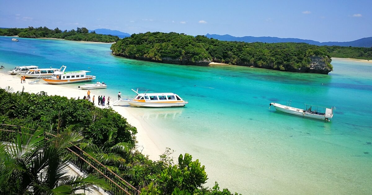 透明な海に浮かぶ遊覧船と緑の小島