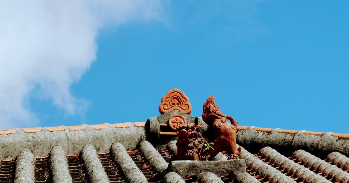 赤瓦屋根の上に並ぶシーサーと青空