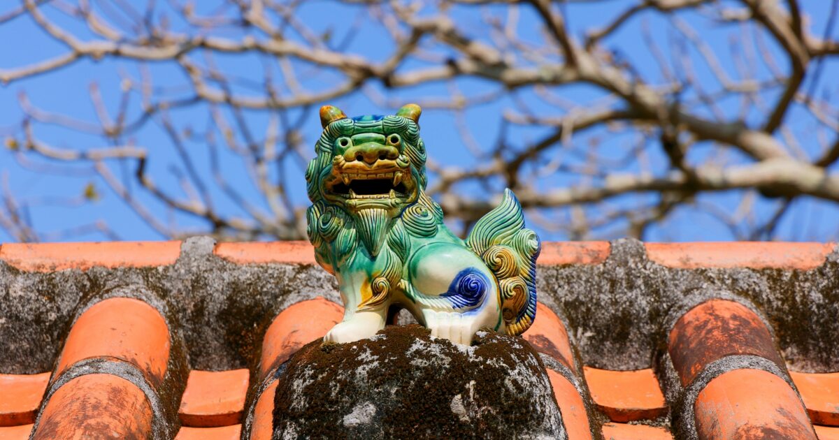 赤瓦屋根の上にあるカラフルなシーサーの置物